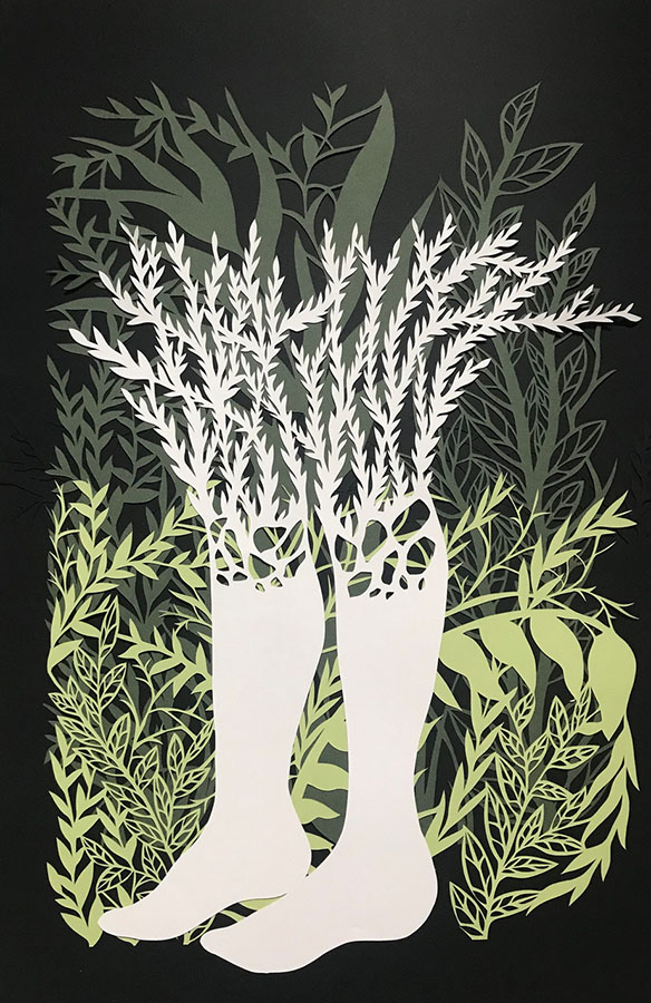 An intricate paper cutout of two legs amidst green ferns. Branches grow out of the top of the legs.